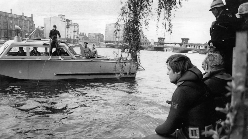 Westtberliner Feuerwehrtaucher wollten vor 50 Jahren den kleinen Cetin aus der Spree retten. Doch DDR-Grenzer (Hintergrund) verweigern den Helfern den Einsatz im damaligen Grenzgewässer.
