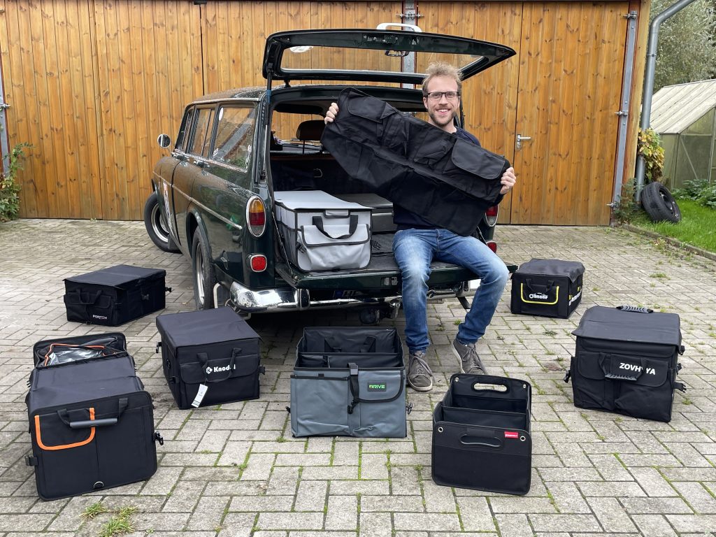 Redakteur sitzt im Kofferraum eines alten Volvo Kombi. Vor ihm aufgereiht liegen Kofferraum-Organizer.