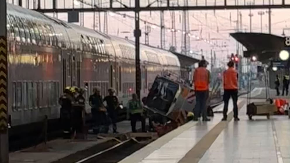 Einsatzkräfte stehen um das zur Seite gekippte Fahrzeug im Gleis 8 herum.