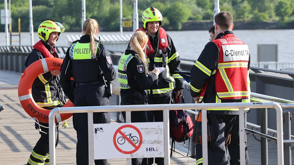 Einsatzkräfte besprechen sich in Teufelsbrück an der Elbe
