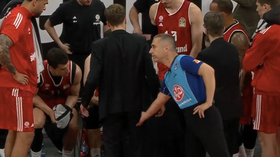 Schiri Lottermoser erinnert die Bayern mit einem gezielten Griff ans Hinterteil, dass die Auszeit vorbei ist