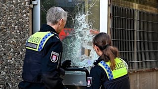 Polizisten sichern Spuren an der eingeschlagenen Scheibe, finden dort auch Blutspuren