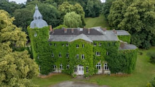 Das Schloss liegt abgeschieden mitten im Grünen, an der gesamten Fassade ranken Pflanzen