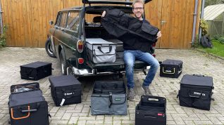 Redakteur sitzt im Kofferraum eines alten Volvo Kombi. Vor ihm aufgereiht liegen Kofferraum-Organizer.