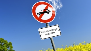 Symbolbild: Straße mit Verbotsschild für Verbrennungsmotoren mit austretendem Qualm
