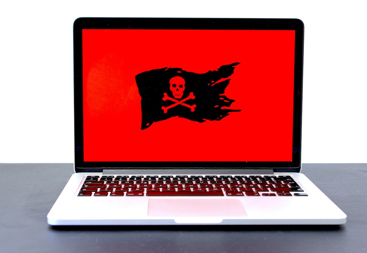 Aufgeklappter Laptop mit rotem Bildschirm und schwarzer Piratenflagge