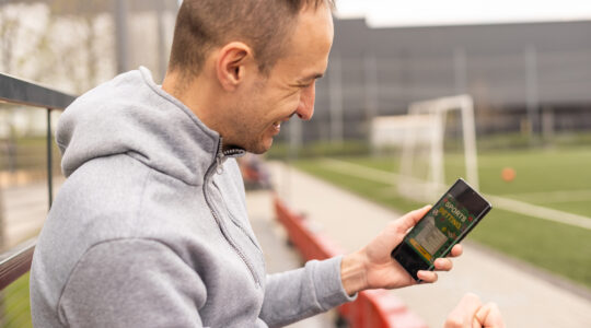 Mann benutzt App auf Tribüne