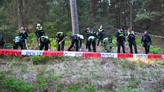 Polizisten mit blauen Gummi-Handschuhen durchsuchen den Waldboden