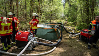 Hubschrauber der Polizei versuchen, mit Löschwasserbehältern die Brandherde zu erreichen