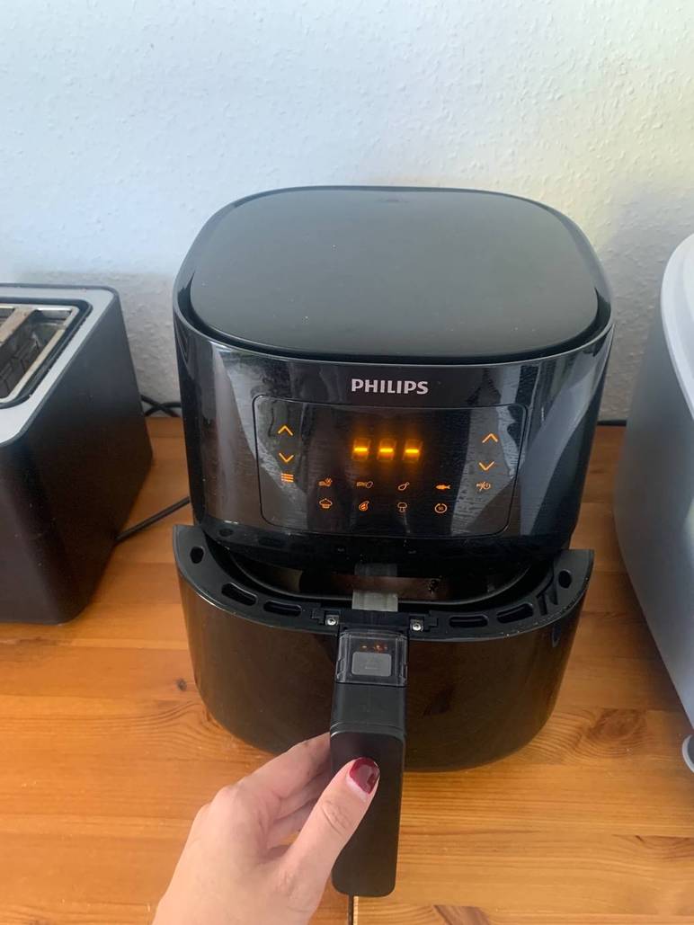 Gesamtansicht einer Philips Airfryer XL HD9270/90 Heißluftfritteuse im Test. Hand öffnet die Schublade des Geräts, das auf einer Holzarbeitsplatte steht.